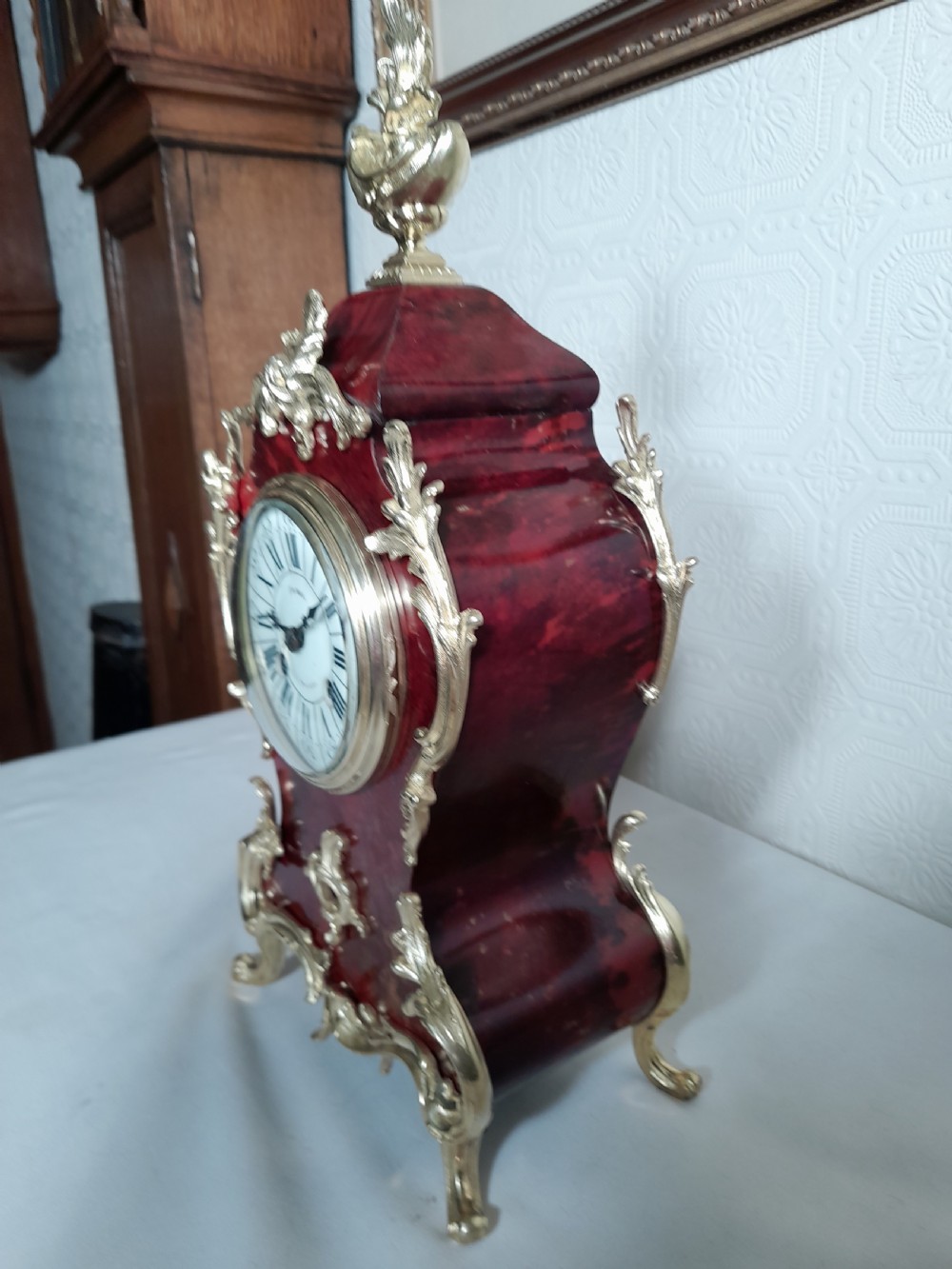 A French Rococo Revival style mantel clock featuring crimson tortoiseshell veneering, ornate gilt bronze mounts, and a white enamel dial with Roman numerals. View III