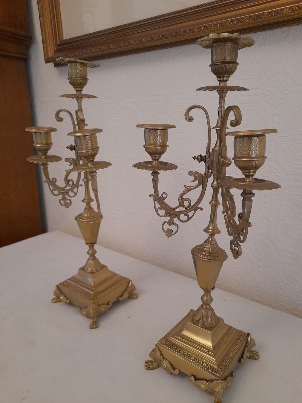 A pair of ornate Victorian cast brass three-light candelabra with scrolled arms, decorative sconces, and square stepped bases supported by paw feet. View II