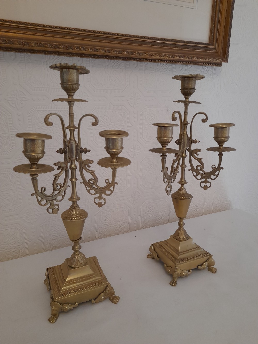 A pair of ornate Victorian cast brass three-light candelabra with scrolled arms, decorative sconces, and square stepped bases supported by paw feet. View III