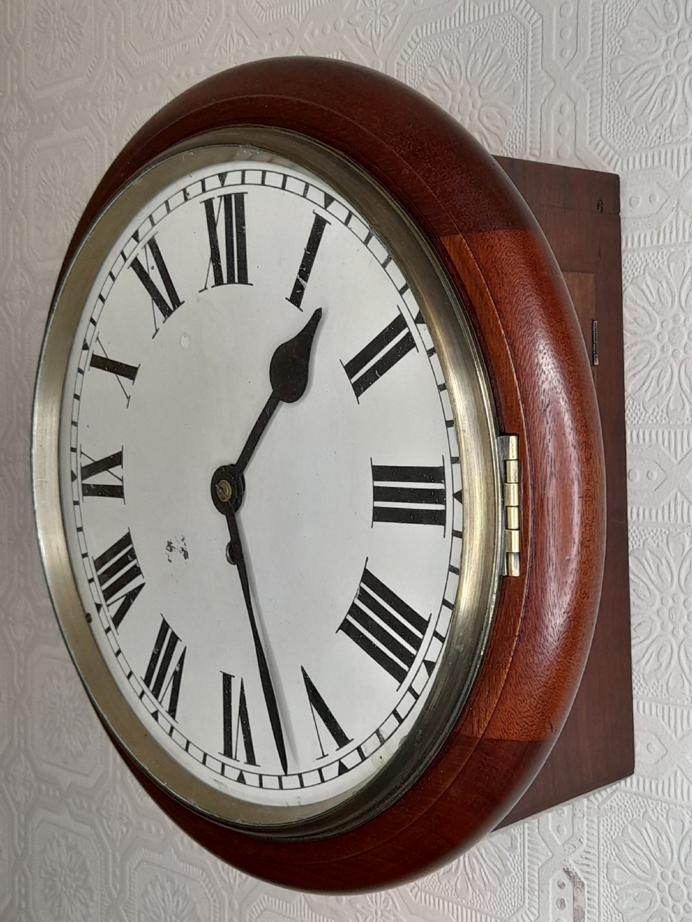 A circular mahogany fusee wall clock featuring a white painted dial with black Roman numerals, black hands, and a hinged brass bezel. View II
