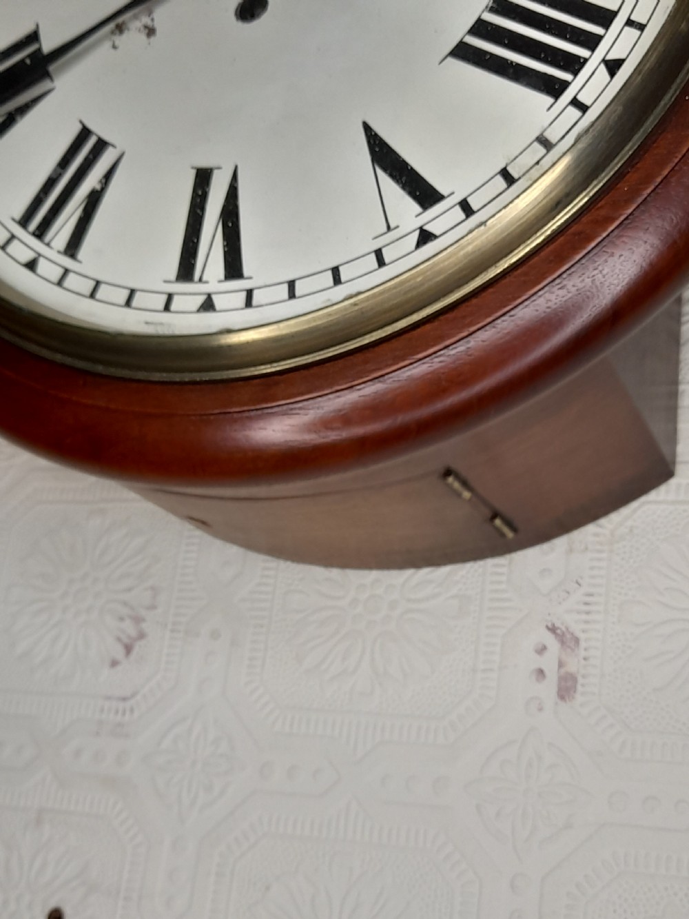 A circular mahogany fusee wall clock featuring a white painted dial with black Roman numerals, black hands, and a hinged brass bezel. View III