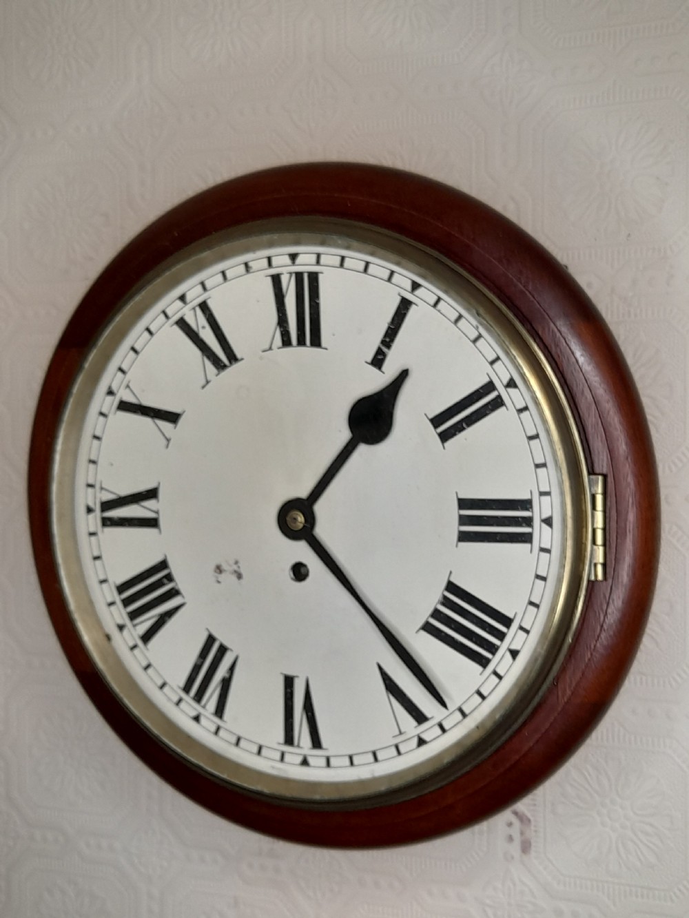 A circular mahogany fusee wall clock featuring a white painted dial with black Roman numerals, black hands, and a hinged brass bezel. View VI