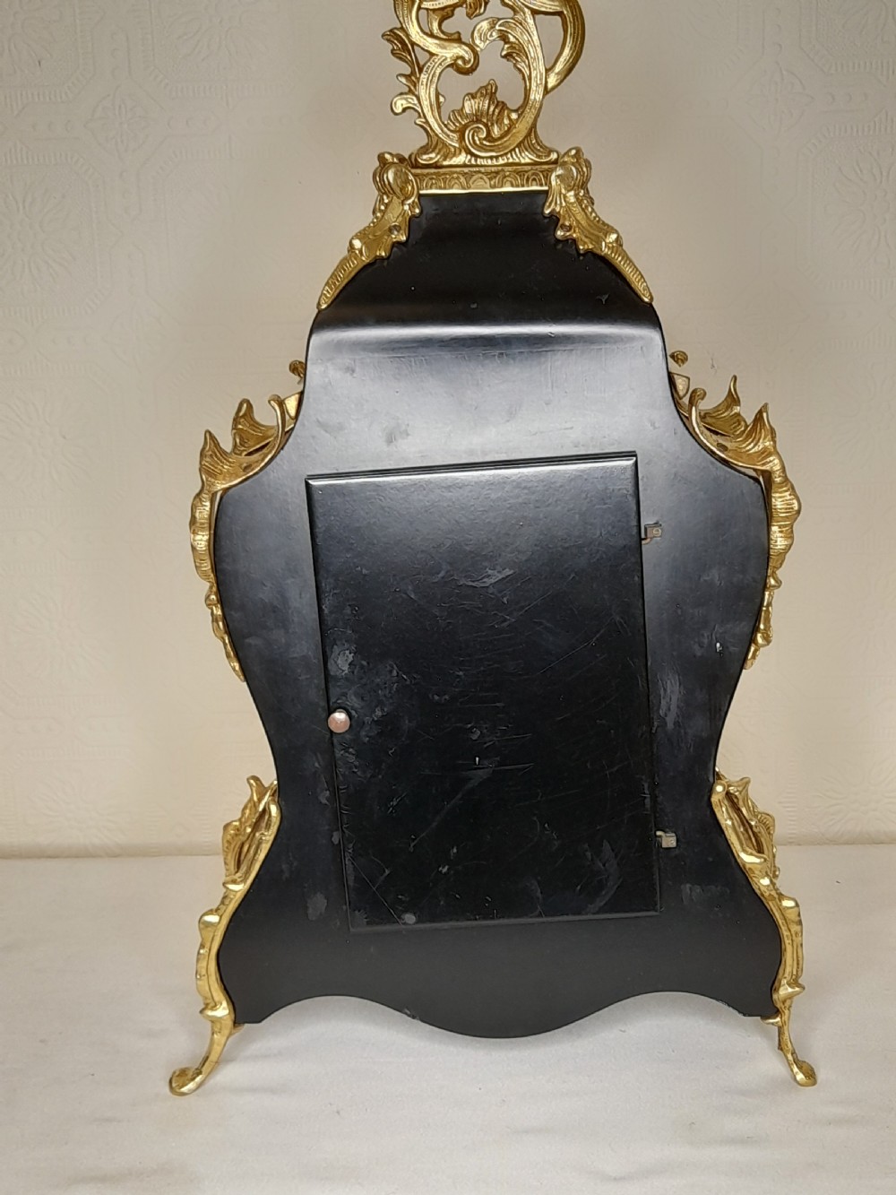 A Louis XIV style bracket clock featuring floral wood marquetry, ornate gilt-bronze mounts, and a dial with white enamel Roman numeral cartouches. View V