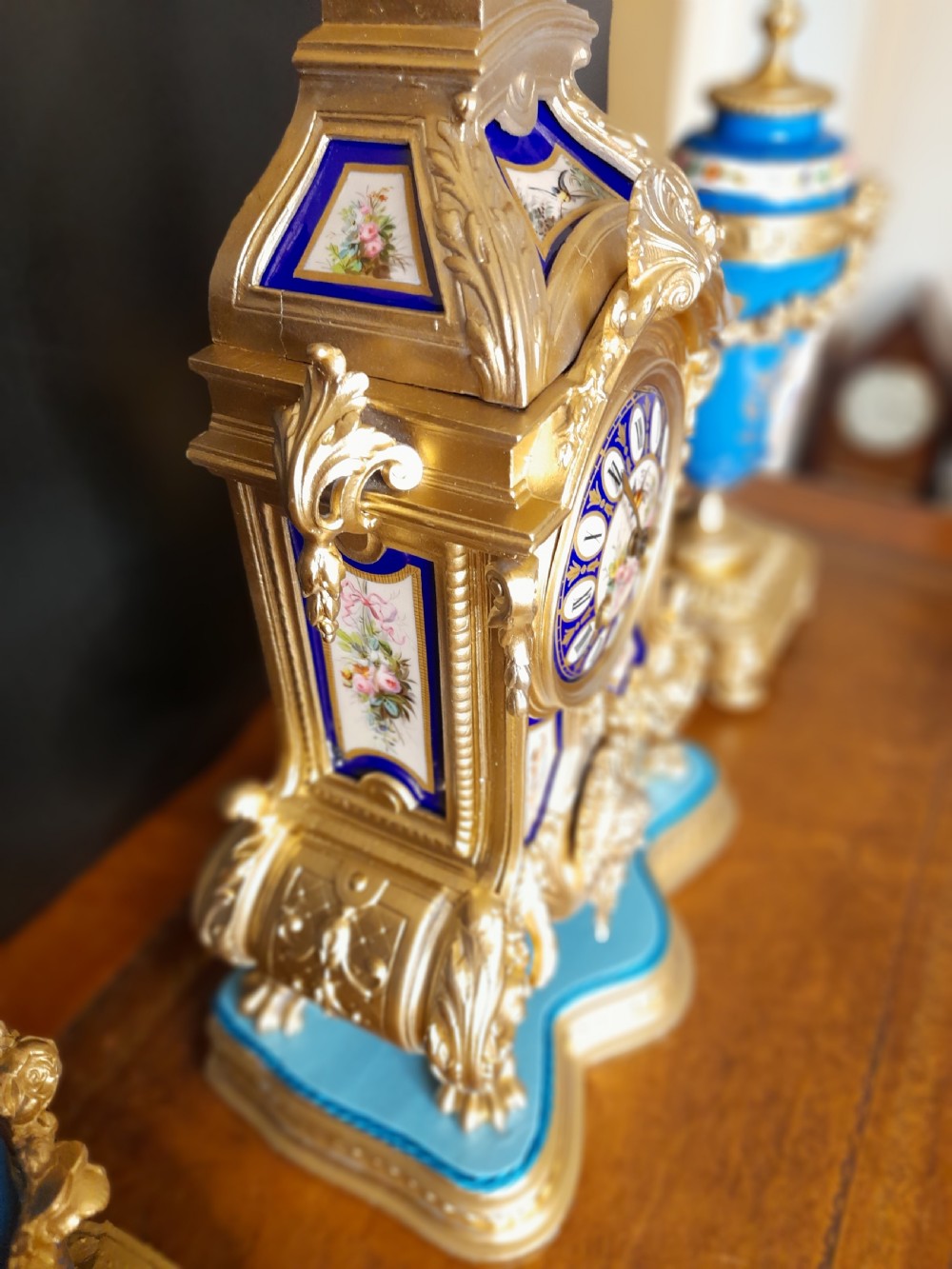 A French gilt bronze clock garniture featuring a central mantel clock with hand-painted blue porcelain panels flanked by two matching ornamental urns. View VIII