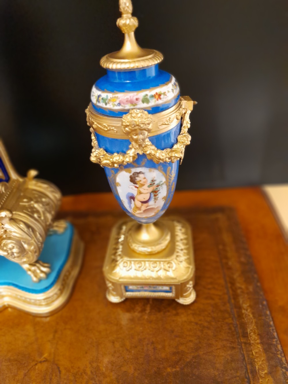 A French gilt bronze clock garniture featuring a central mantel clock with hand-painted blue porcelain panels flanked by two matching ornamental urns. View X