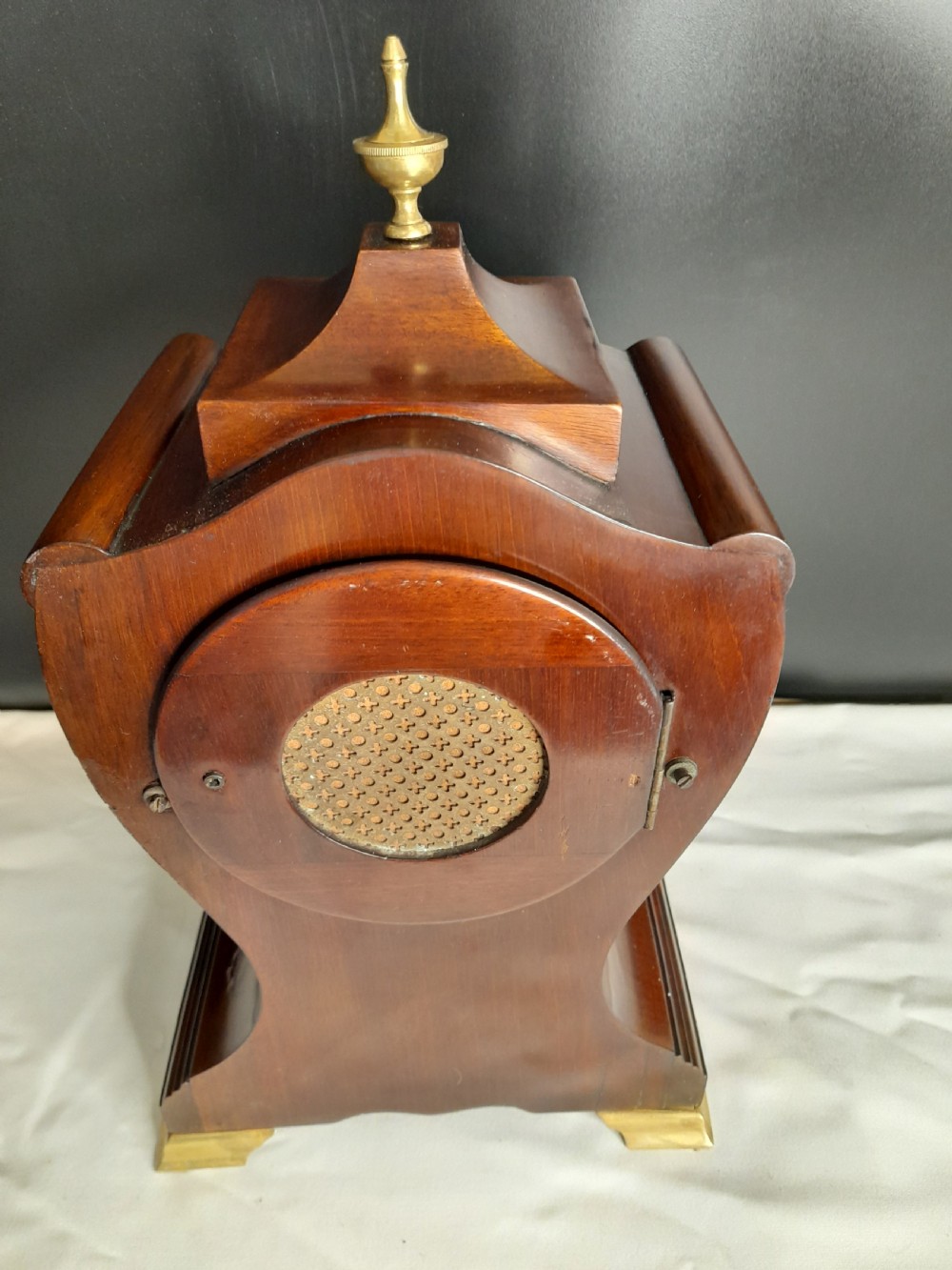 An Art Nouveau satinwood mantel clock featuring floral marquetry inlays, a silvered Roman numeral dial, a brass finial, and brass bracket feet. View VI