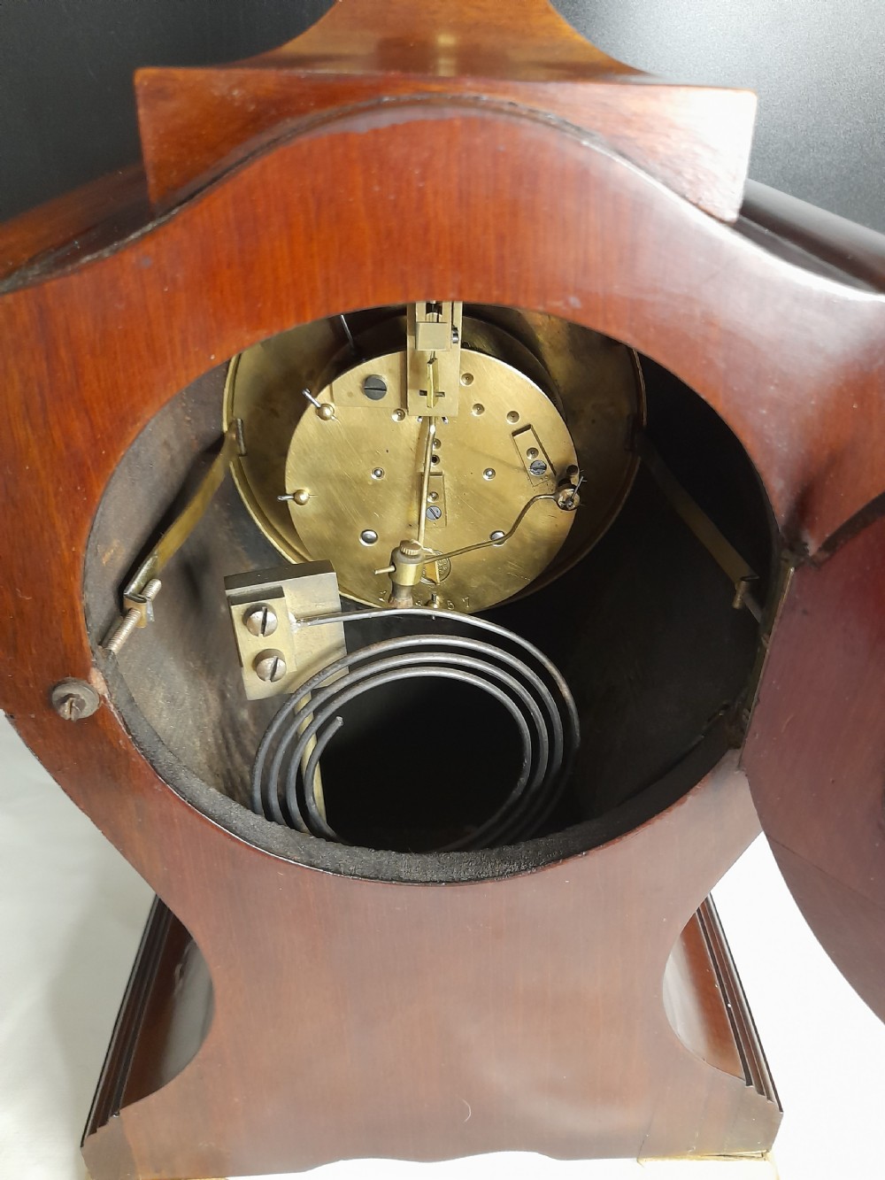 An Art Nouveau satinwood mantel clock featuring floral marquetry inlays, a silvered Roman numeral dial, a brass finial, and brass bracket feet. View VII