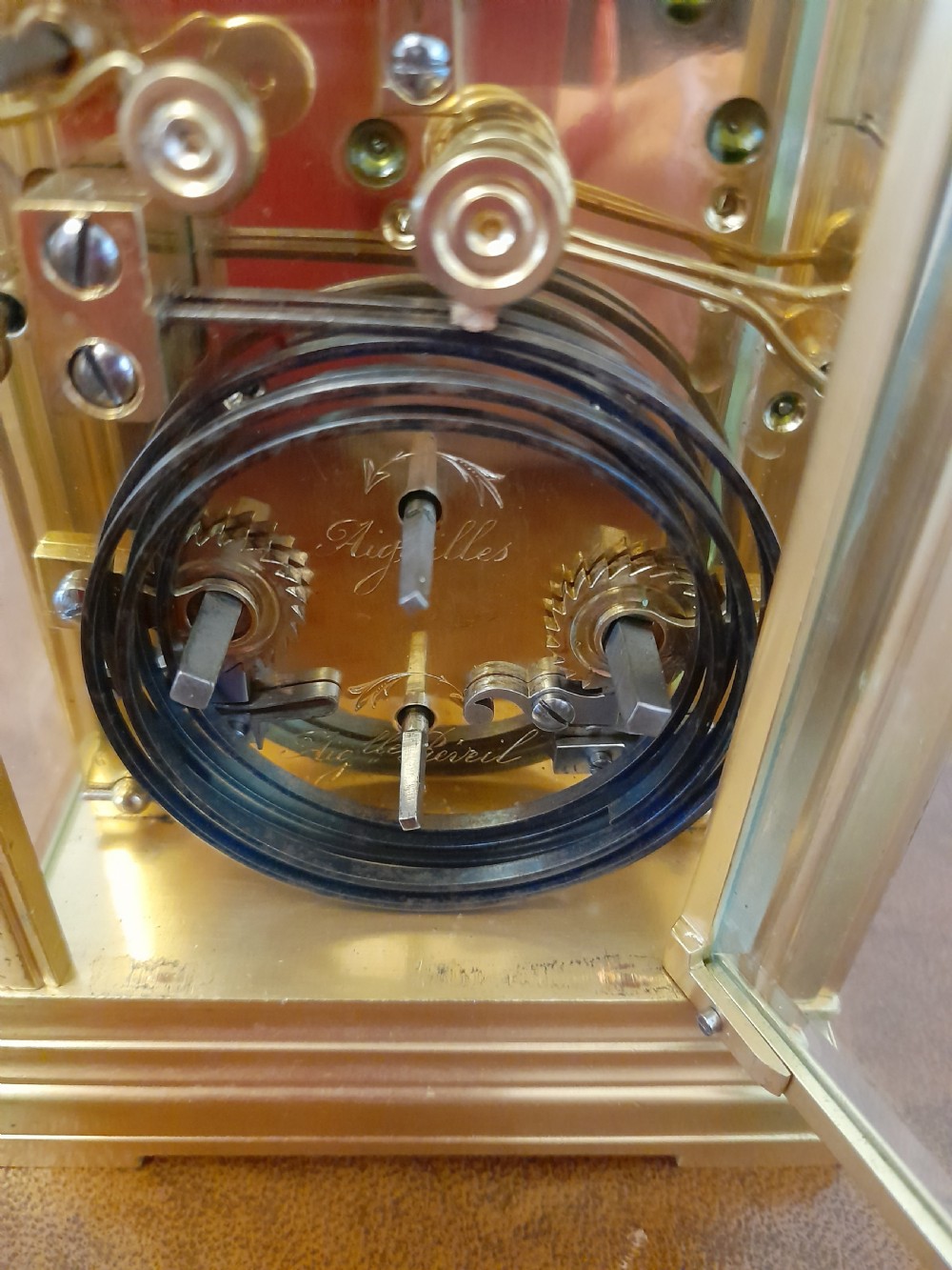 A gilt brass carriage clock featuring a fluted top handle, bevelled glass panels, a white enamel main dial with Arabic numerals, an alarm sub-dial, and an accompanying winding key. View VIII