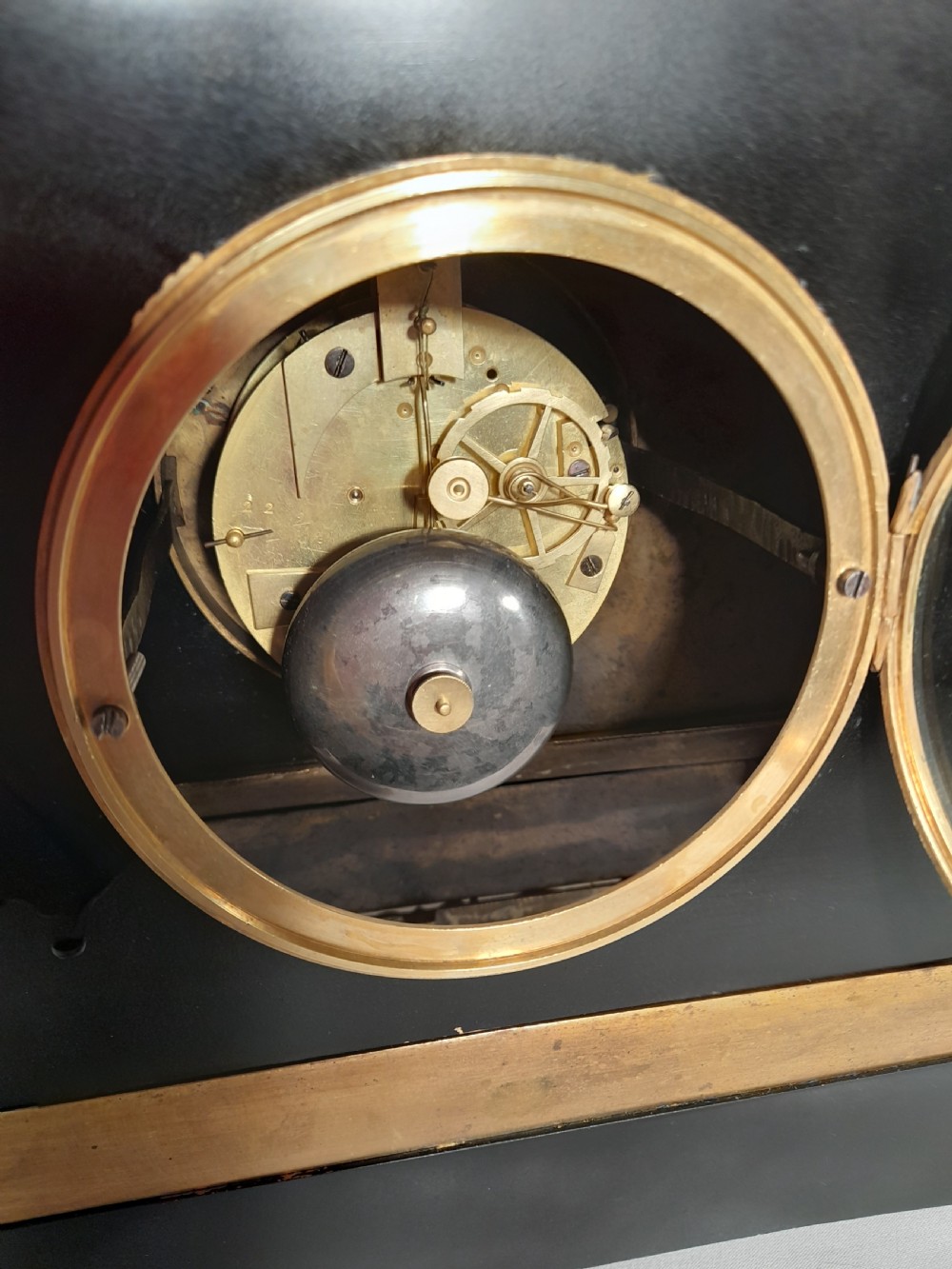 A French Empire style mantel clock featuring a gilded lion sculpture on top of a black rectangular casing adorned with gold acanthus mounts and a central clock dial. View VI