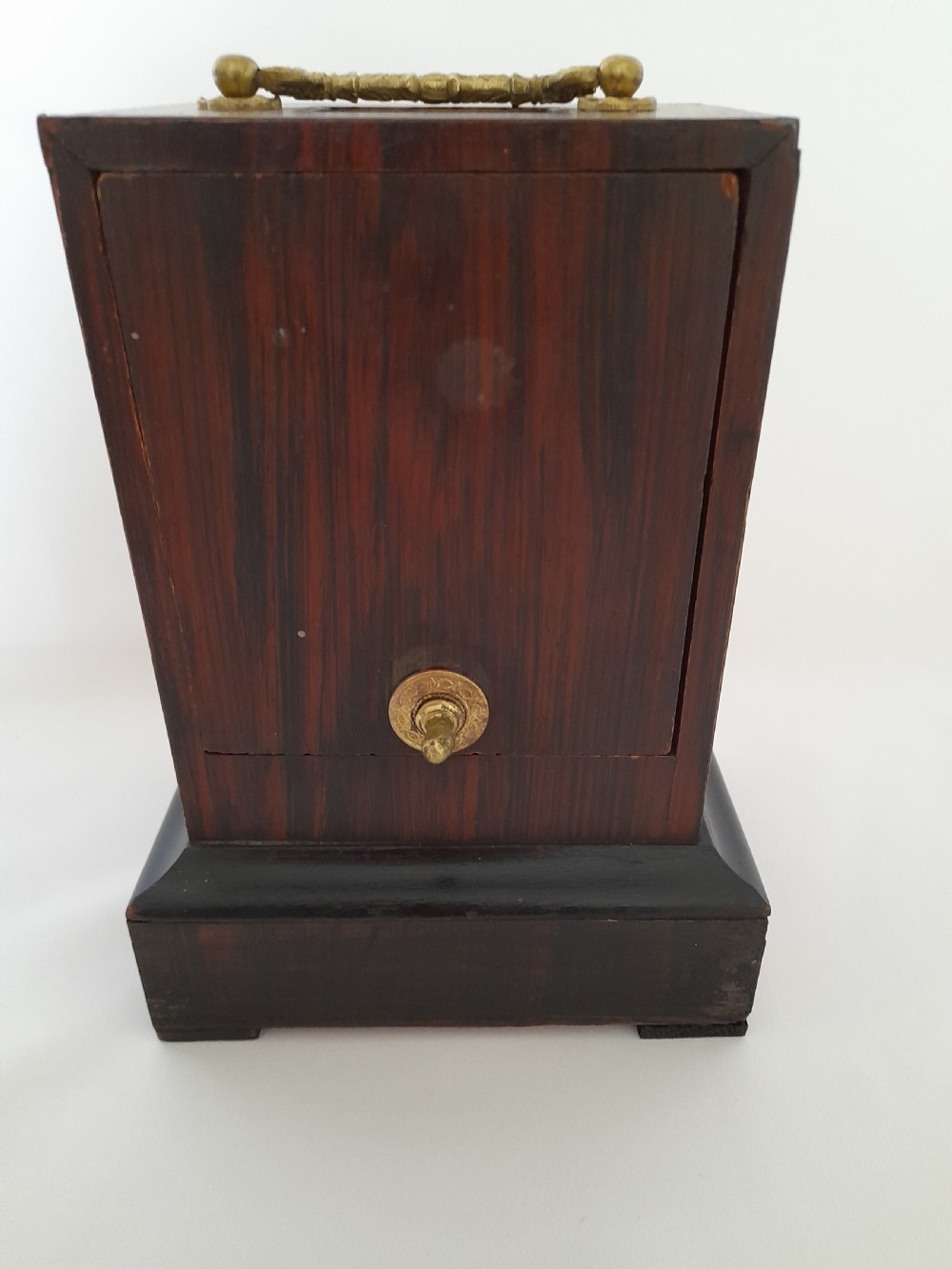 An antique French officers clock with a dark wood inlaid rectangular case, a decorative brass carrying handle, and a white enamel clock face with Roman numerals. View VII