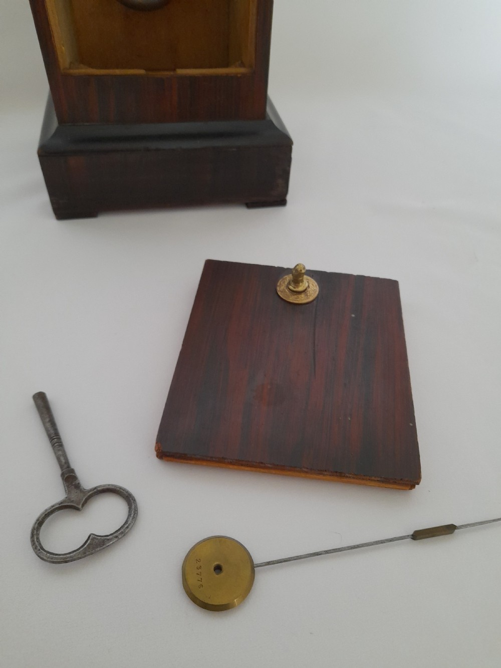 An antique French officers clock with a dark wood inlaid rectangular case, a decorative brass carrying handle, and a white enamel clock face with Roman numerals. View VIII