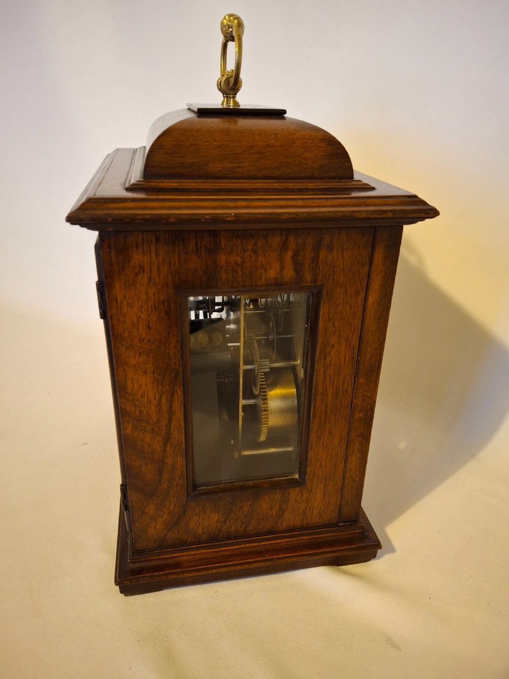 An Art Nouveau mahogany mantel clock featuring a balloon-shaped case with inlaid urn marquetry, boxwood stringing, a circular white dial with Roman numerals, and a brass bezel. View XII