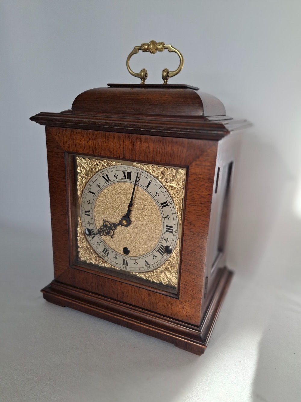 An Art Nouveau mahogany mantel clock featuring a balloon-shaped case with inlaid urn marquetry, boxwood stringing, a circular white dial with Roman numerals, and a brass bezel. View XIII