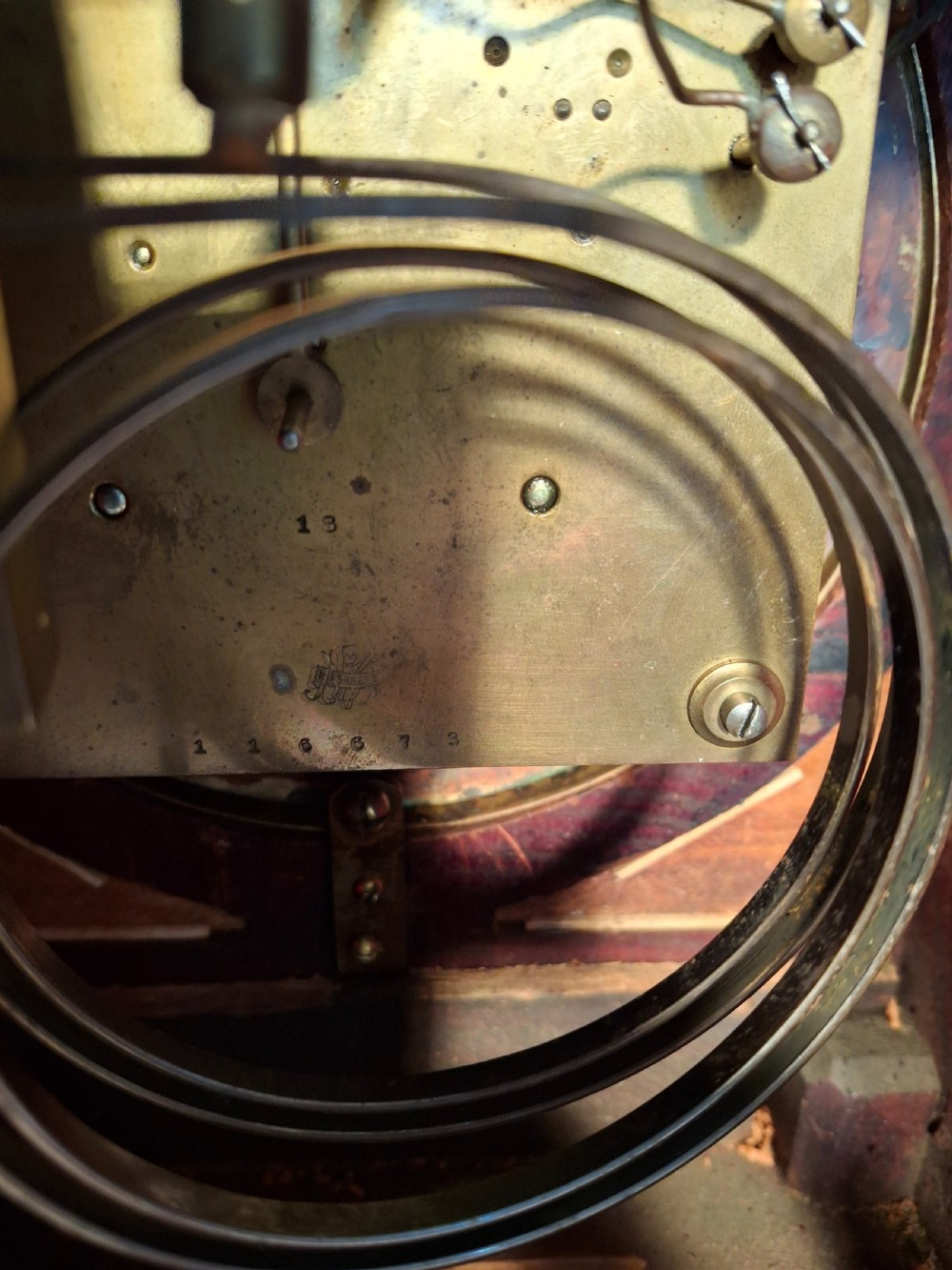 A mahogany pad-top bracket clock featuring a brass carrying handle, circular dial with Roman numerals, side sound frets, and brass feet. View III