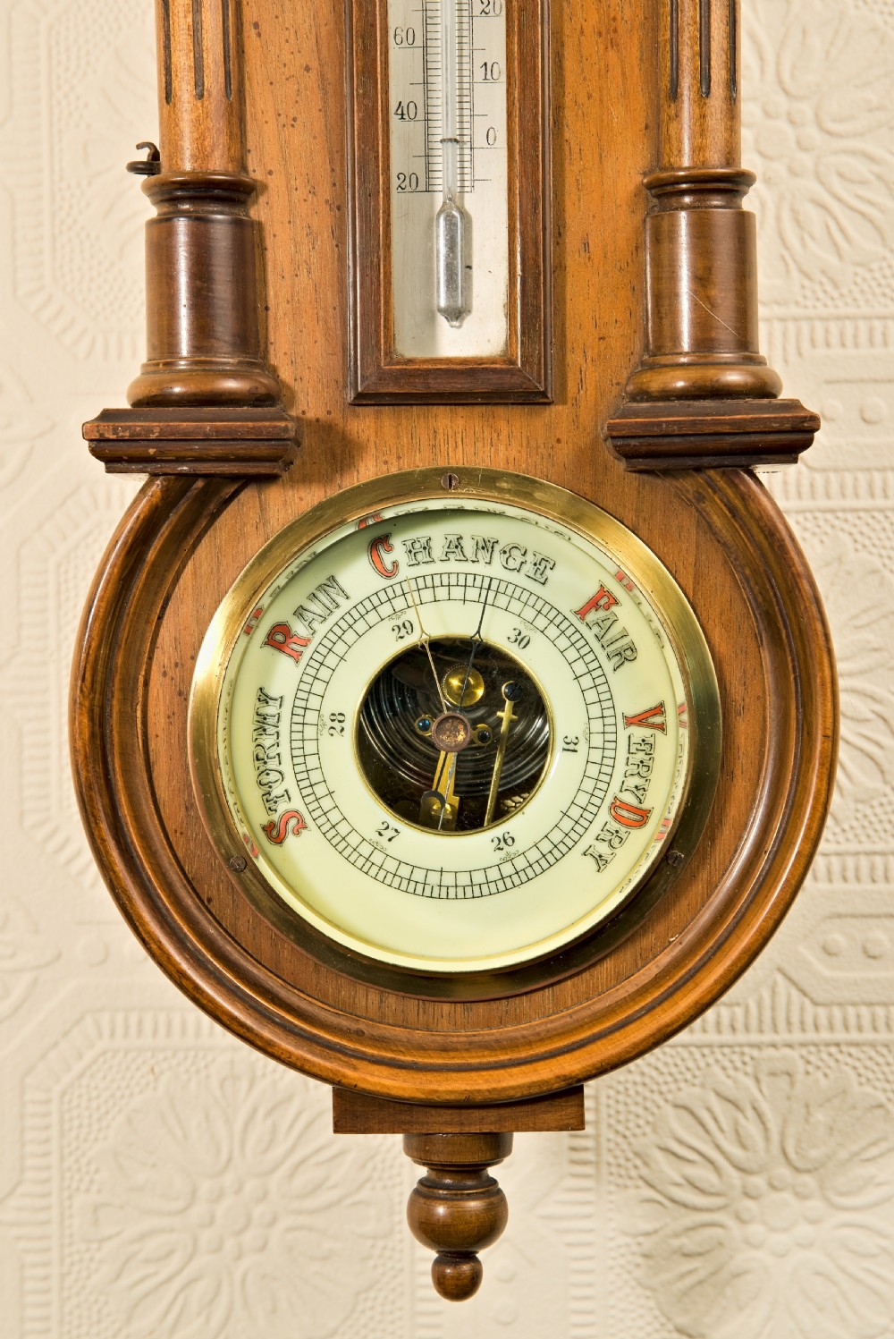 A wall-hung antique walnut clock, thermometer, and aneroid barometer companion set featuring carved pediment ornamentation and brass-rimmed dials. View VI