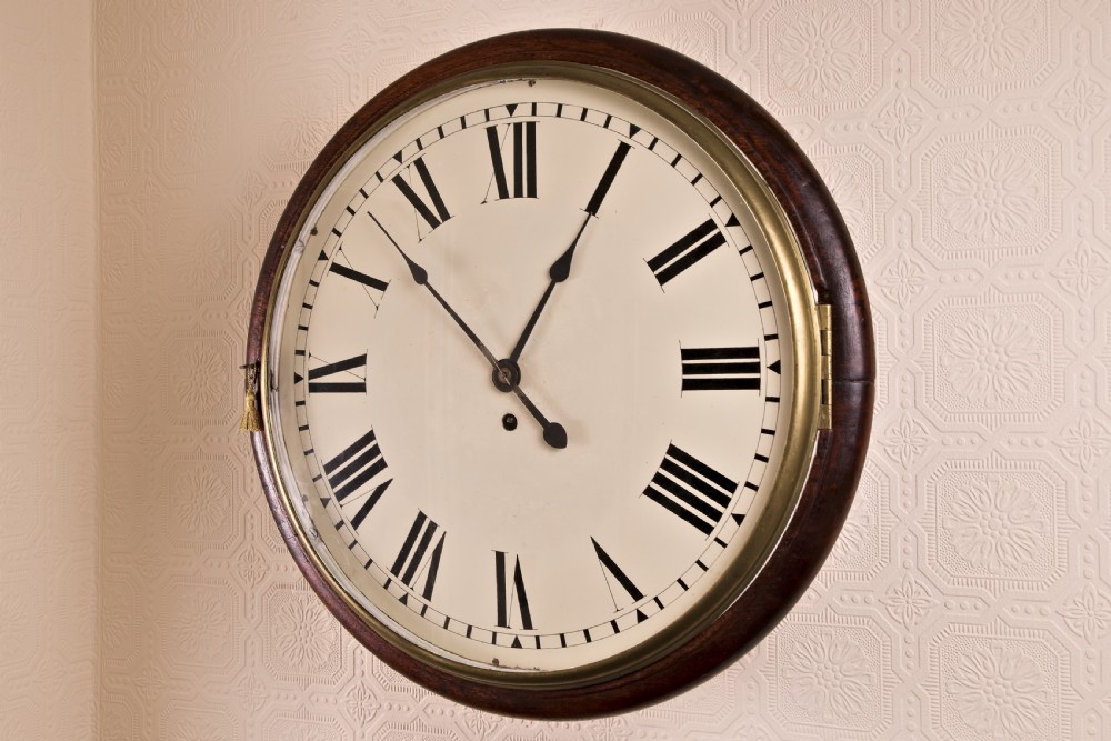 A large circular antique wall clock featuring a dark mahogany surround, turned brass bezel, and a cream dial with black Roman numerals. View II