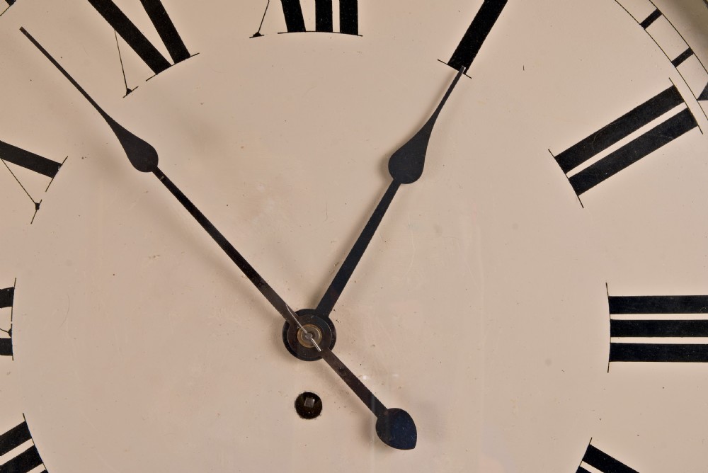 A large circular antique wall clock featuring a dark mahogany surround, turned brass bezel, and a cream dial with black Roman numerals. View V