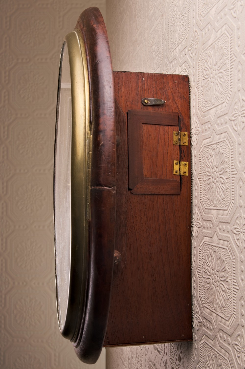 A large circular antique wall clock featuring a dark mahogany surround, turned brass bezel, and a cream dial with black Roman numerals. View VII