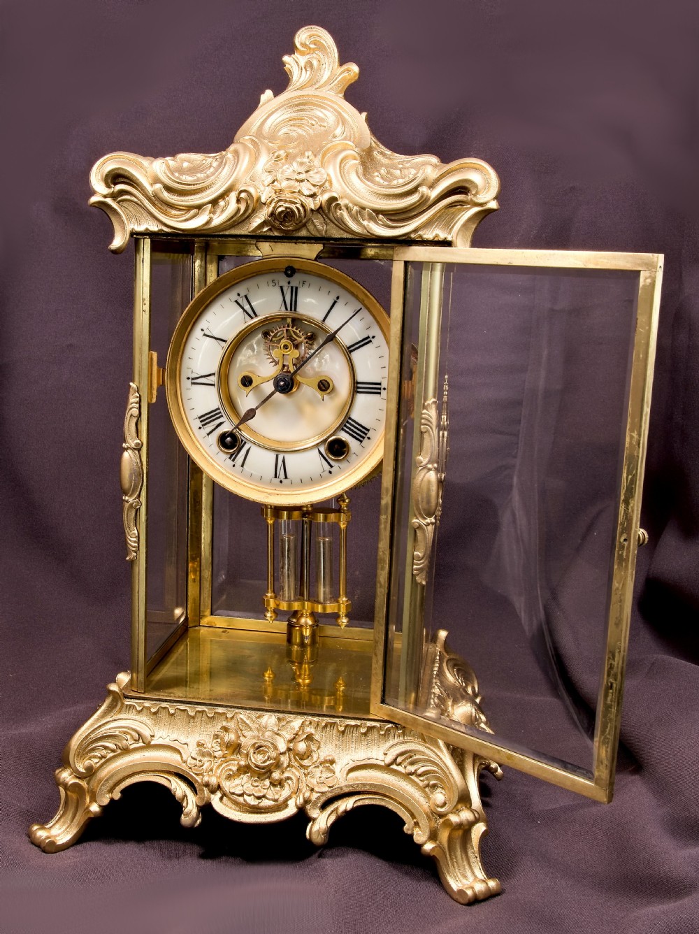 A 19th-century Rococo Revival gilt bronze four-glass mantel clock featuring scrollwork cresting, a white enamel dial, and a visible mercury pendulum. View II