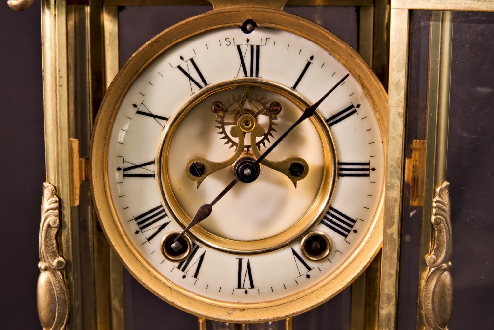 A 19th-century Rococo Revival gilt bronze four-glass mantel clock featuring scrollwork cresting, a white enamel dial, and a visible mercury pendulum. View III