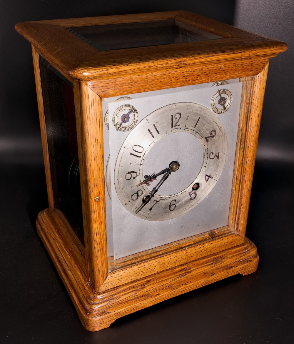 An antique golden oak four-glass bracket clock featuring a silvered brass dial with subsidiary chime controls.