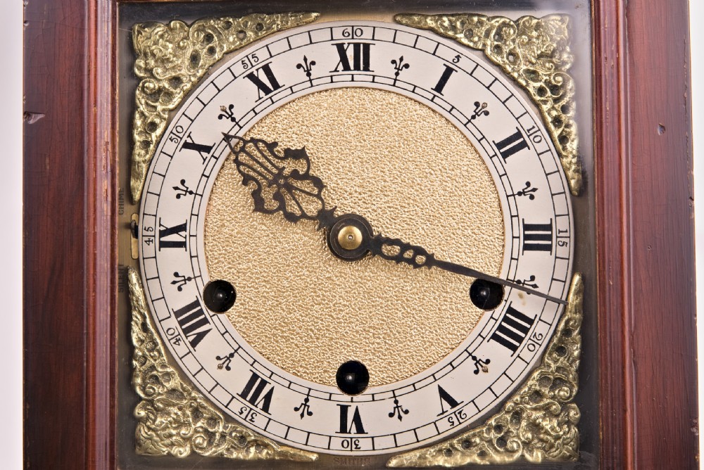 A dark mahogany wooden bracket mantel clock featuring a brass dial with Roman numerals, cast brass spandrels, glass side panels, and a brass carrying handle on top. View IX
