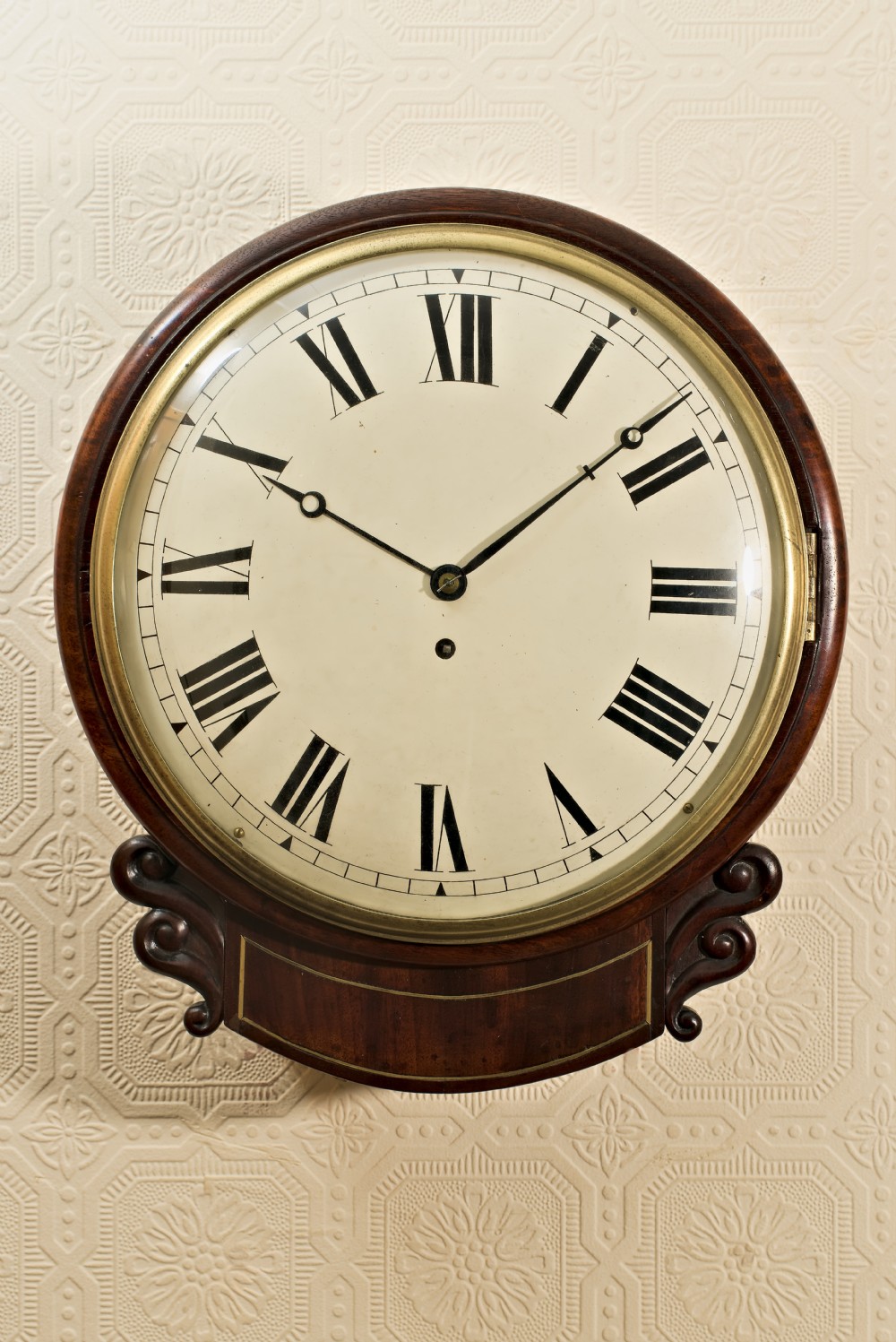 A Victorian mahogany fusee wall clock featuring a cream painted dial with Roman numerals, a brass bezel, and carved side scroll ears. View XIV