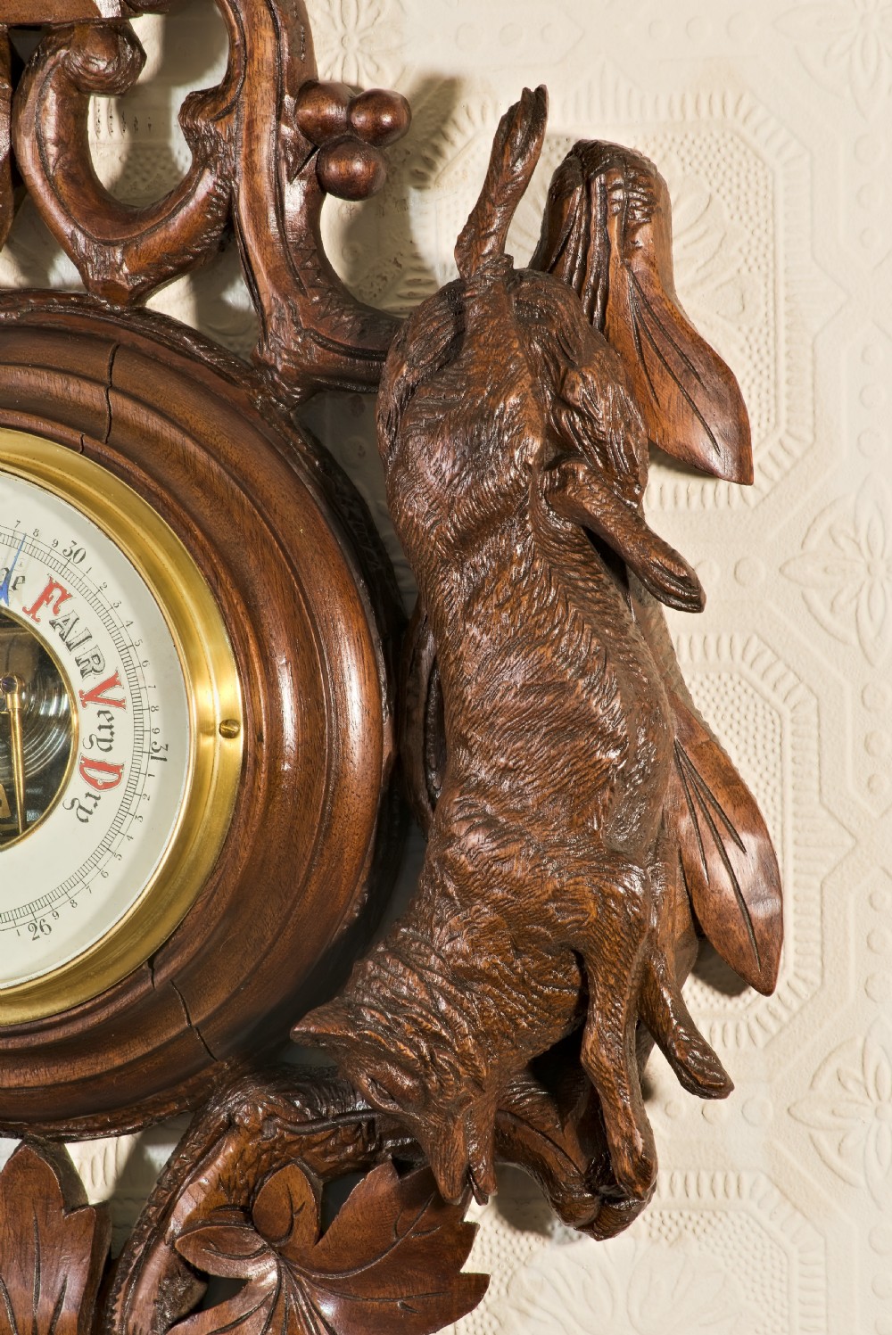 A late 19th-century Black Forest carved wooden wall barometer featuring a chamois head at the top, flanked by carved game animals and foliage around a central dial and upper thermometer tube. View III