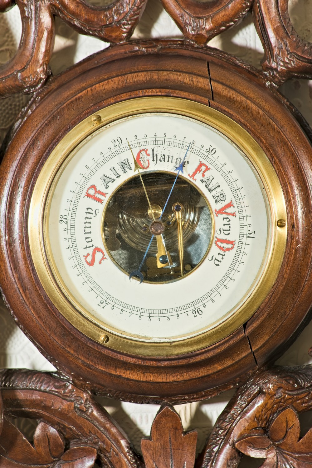 A late 19th-century Black Forest carved wooden wall barometer featuring a chamois head at the top, flanked by carved game animals and foliage around a central dial and upper thermometer tube. View V