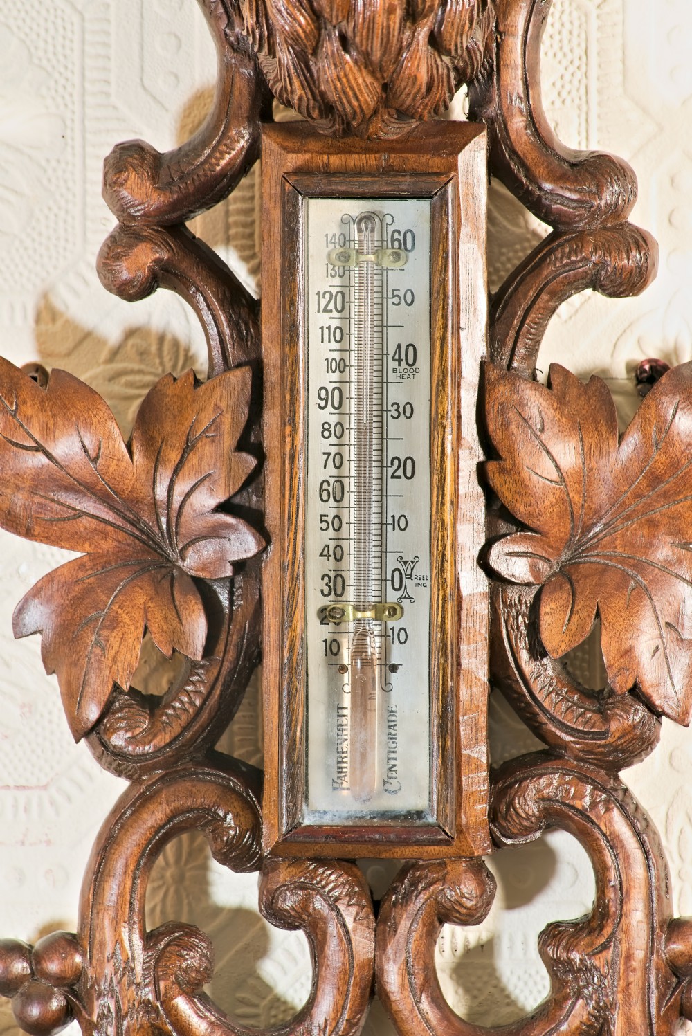 A late 19th-century Black Forest carved wooden wall barometer featuring a chamois head at the top, flanked by carved game animals and foliage around a central dial and upper thermometer tube. View VI