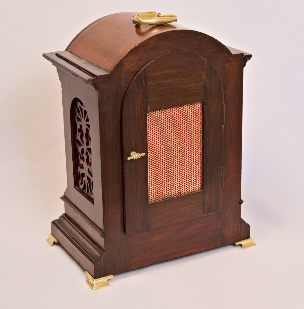 An Edwardian inlaid mahogany arch-top mantel clock with a brass-bezel dial, Roman numerals, side sound frets, and brass corner feet. View III