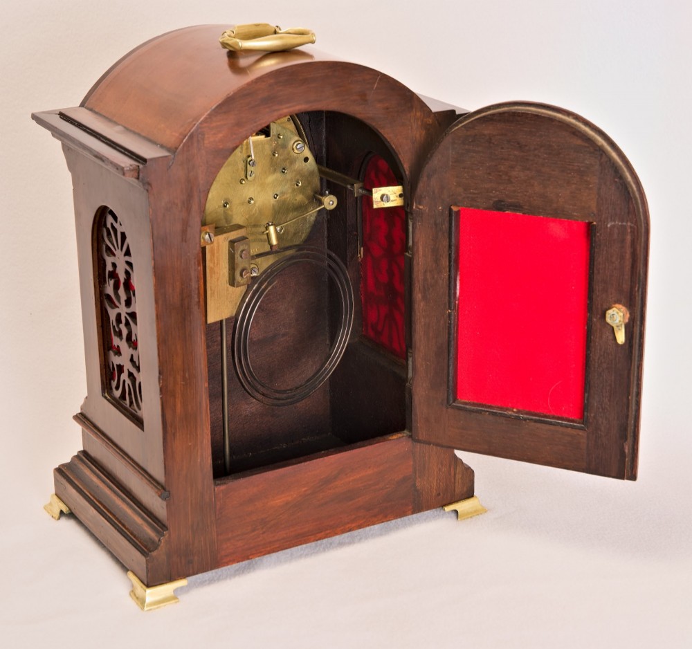 An Edwardian inlaid mahogany arch-top mantel clock with a brass-bezel dial, Roman numerals, side sound frets, and brass corner feet. View IV