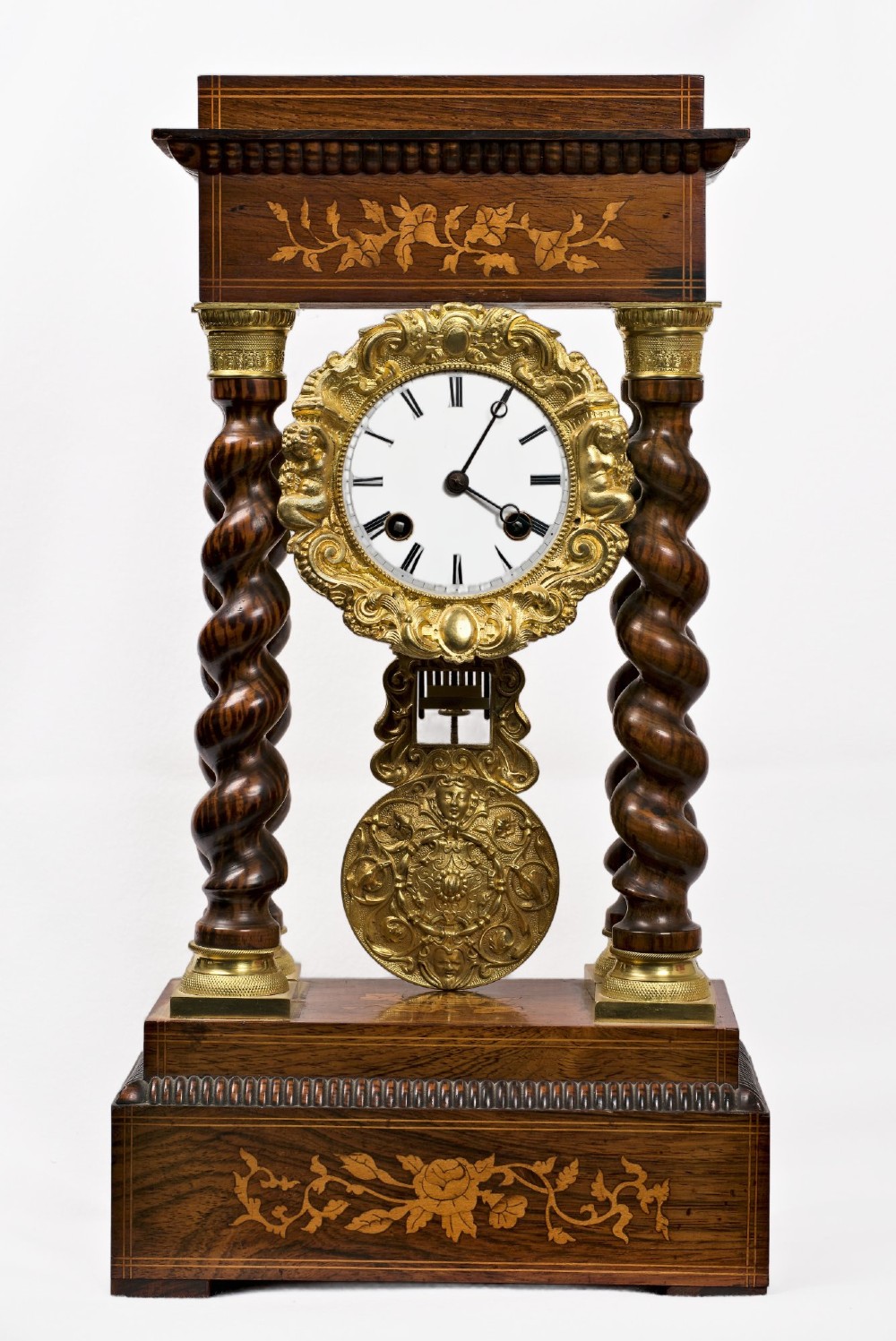 A 19th-century rosewood portico clock featuring floral marquetry inlays, twin barley-twist columns with gilt capitals, and a white enamel dial with an ornate gilt bezel.