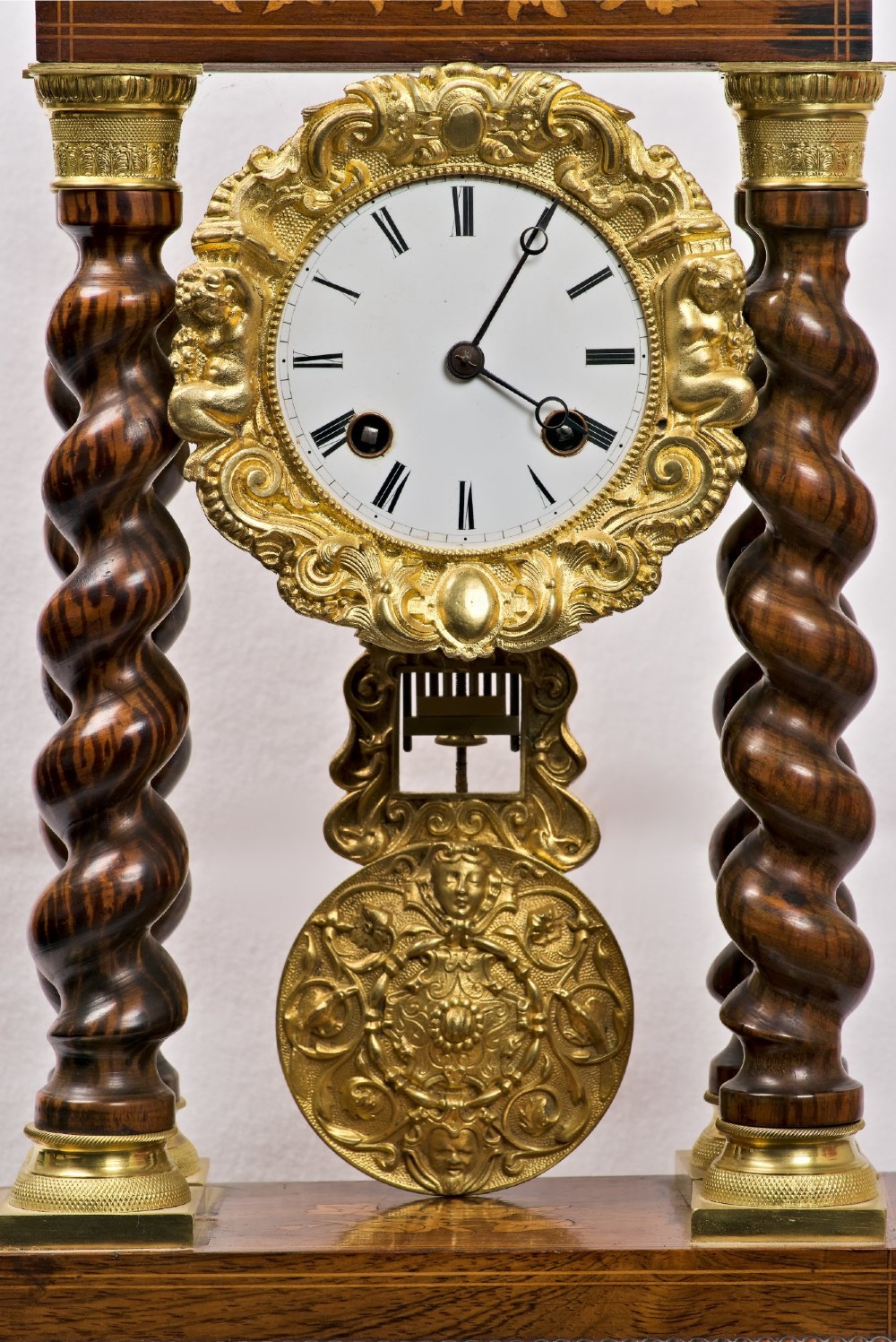A 19th-century rosewood portico clock featuring floral marquetry inlays, twin barley-twist columns with gilt capitals, and a white enamel dial with an ornate gilt bezel. View II