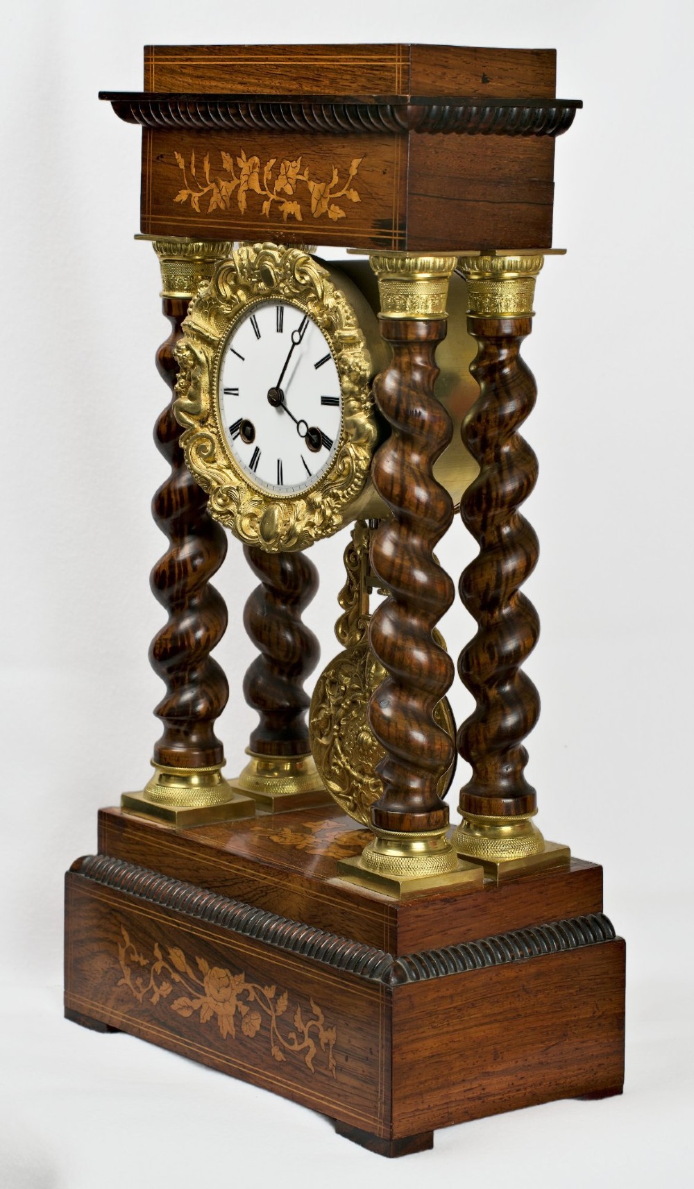 A 19th-century rosewood portico clock featuring floral marquetry inlays, twin barley-twist columns with gilt capitals, and a white enamel dial with an ornate gilt bezel. View VII