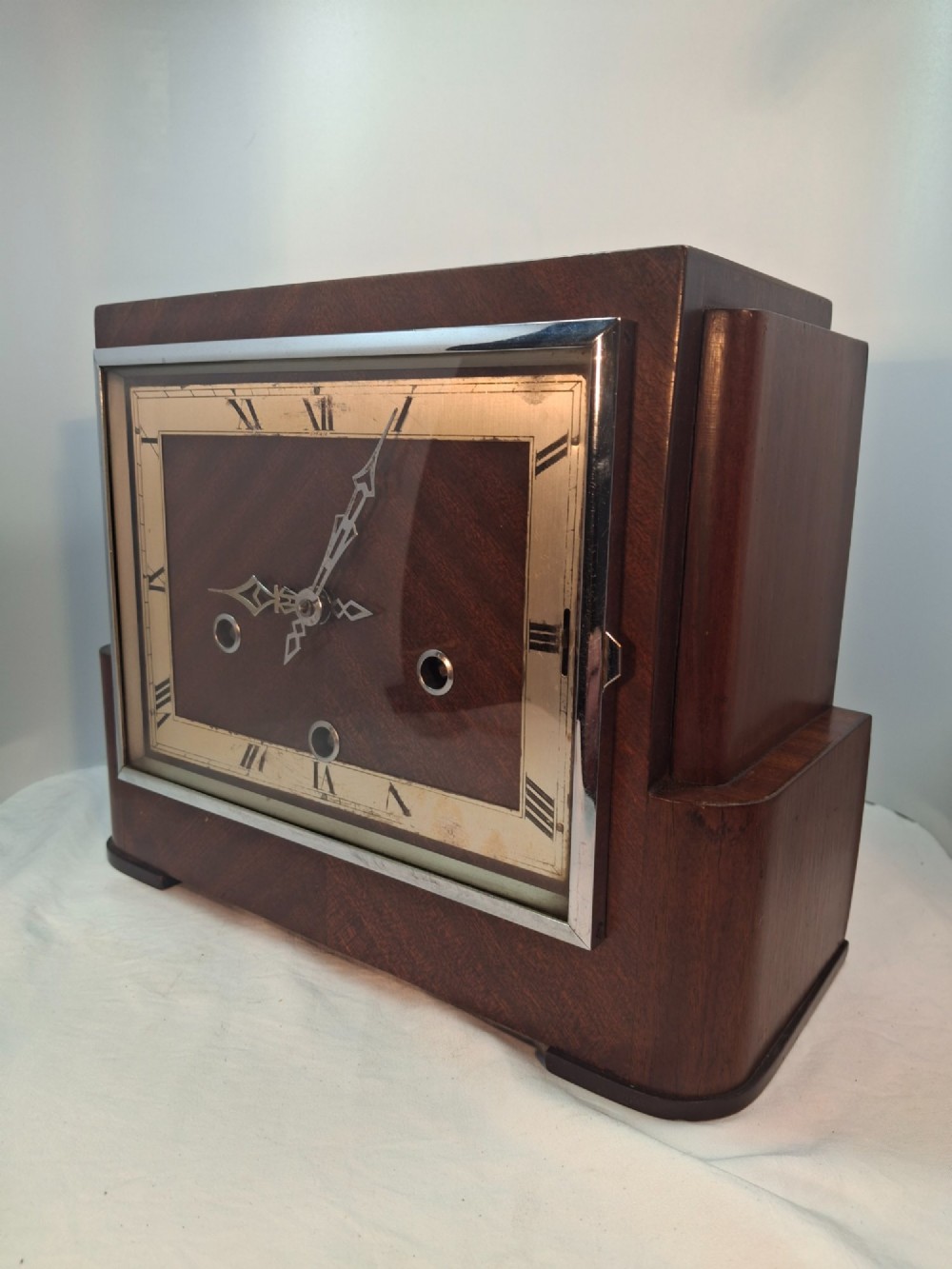 An Art Deco rectangular mantel clock crafted from rich brown walnut veneer featuring a silvered chapter ring with Roman numerals and a chrome-framed glass dial cover. View II