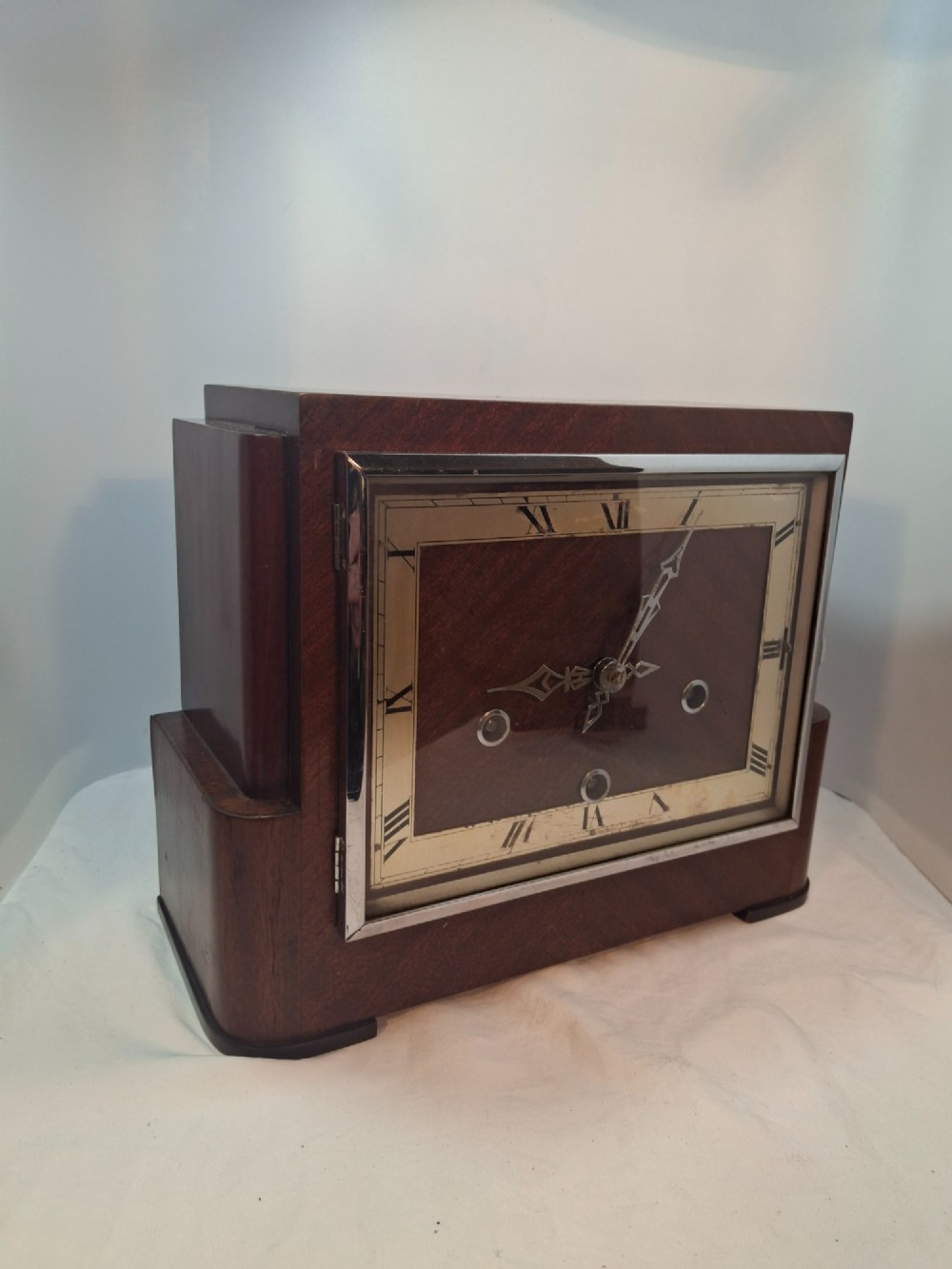 An Art Deco rectangular mantel clock crafted from rich brown walnut veneer featuring a silvered chapter ring with Roman numerals and a chrome-framed glass dial cover. View III