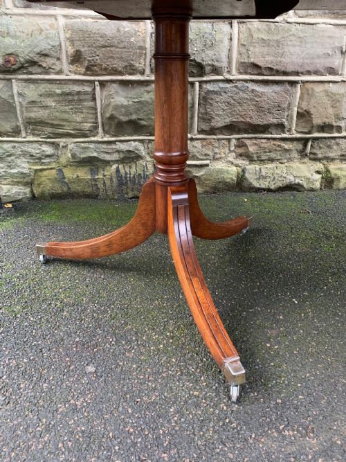 fig 1. A long mahogany extending dining table supported by three pedestal bases with splayed legs and brass castors.