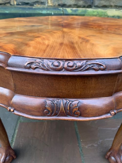 fig 1. A circular low coffee table in figured walnut featuring a scalloped rim, starburst veneer pattern, carved cabriole legs, and claw and ball feet.