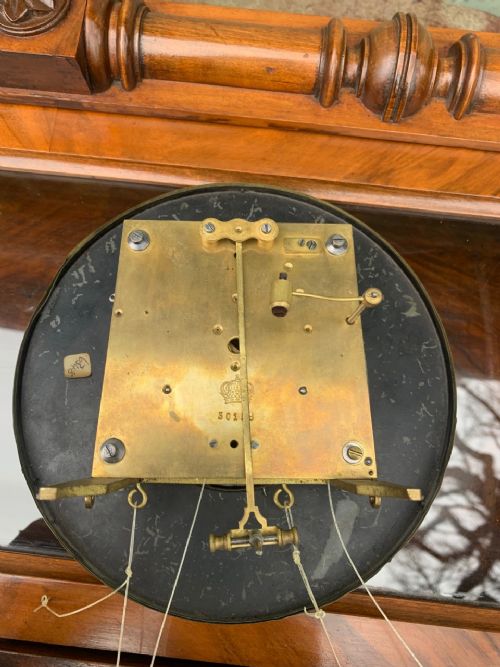 fig 1. An antique walnut Vienna wall clock featuring a carved eagle finial, turned columns, an enamel dial with Roman numerals, two brass weights, and a pendulum.