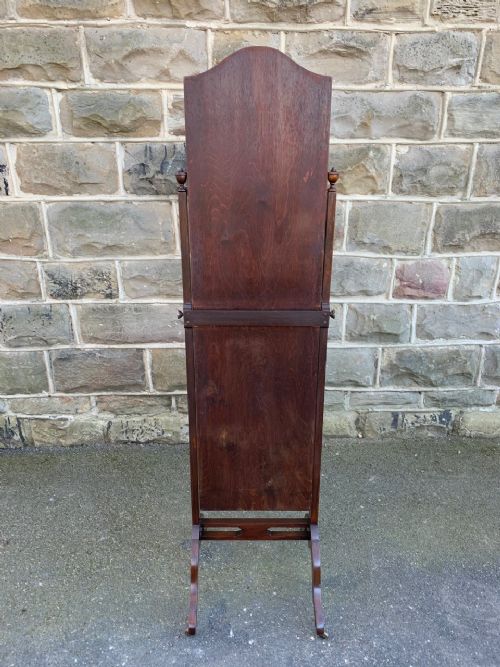 fig 1. An antique mahogany cheval dressing mirror with an arched top frame, turned side supports with finials, and splayed legs with brass castors.