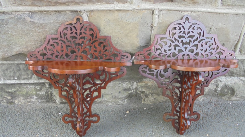 A pair of carved walnut wall brackets featuring pierced fretwork scroll designs and flat top display surfaces. View II