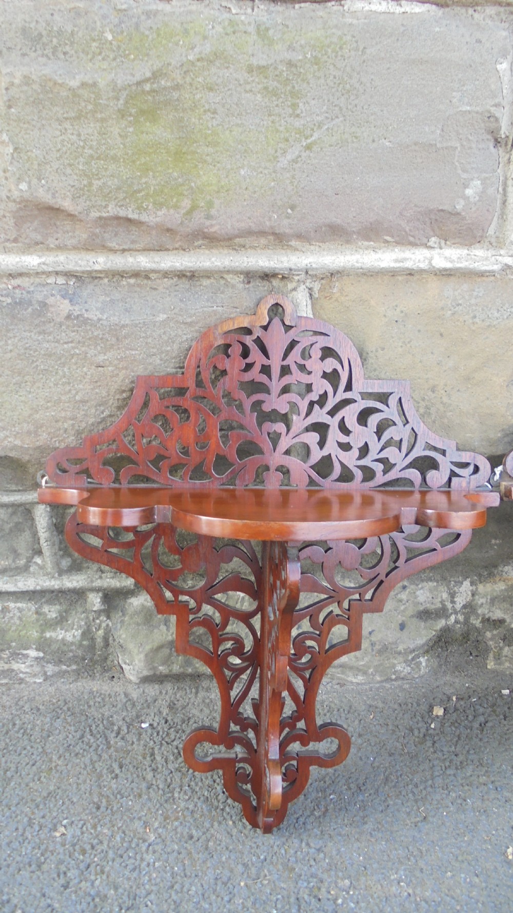 A pair of carved walnut wall brackets featuring pierced fretwork scroll designs and flat top display surfaces. View V