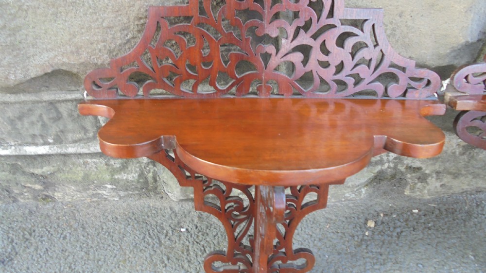 A pair of carved walnut wall brackets featuring pierced fretwork scroll designs and flat top display surfaces. View VI