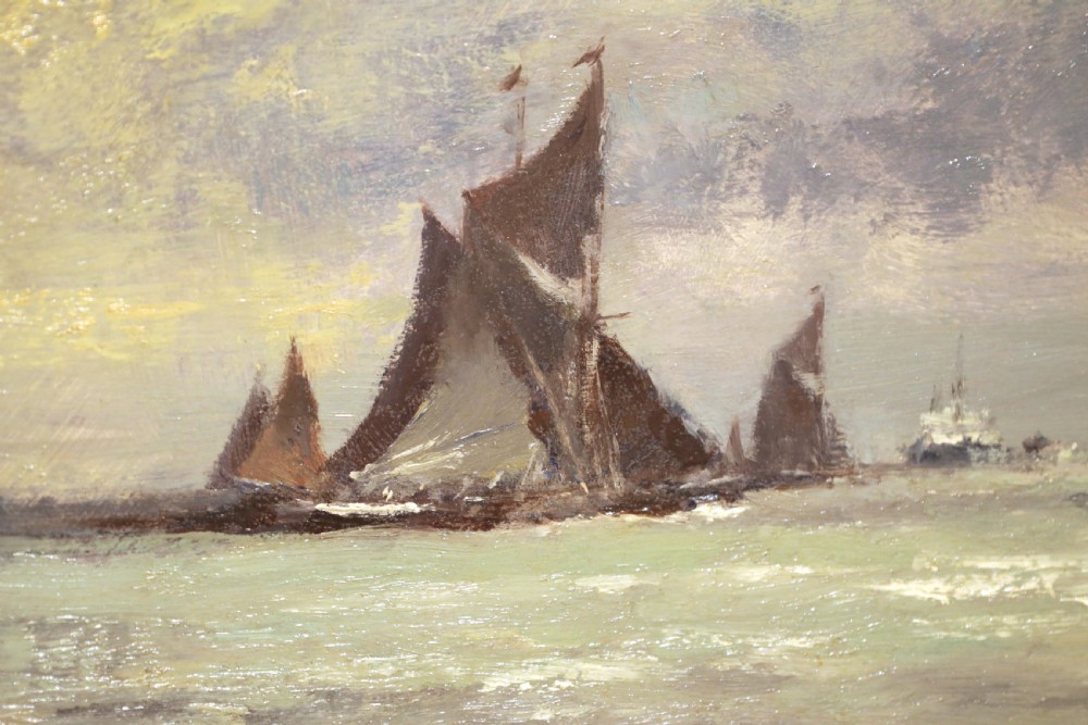 An original oil painting on canvas by Edward Seago depicting sailing boats on calm waters under a dramatic cloudy sky, presented in a molded gold frame. View IV