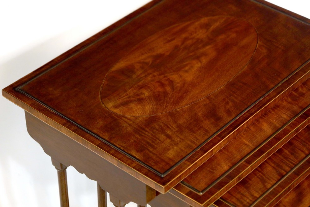 A set of four graduated nesting tables crafted from dark mahogany wood featuring line inlay and slender turned legs. View IV