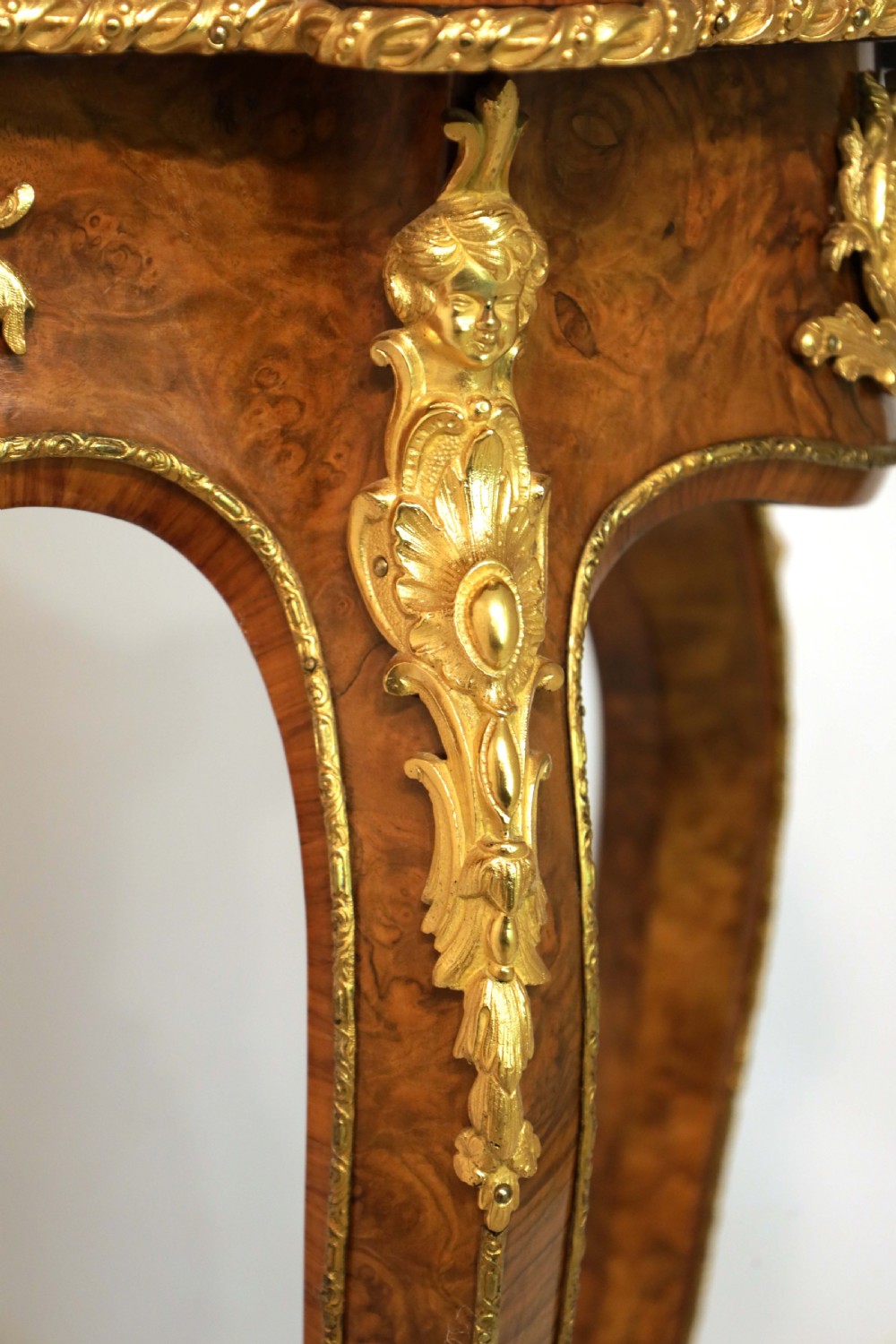 A Victorian burr walnut occasional table featuring a serpentine-edged top, cabriole legs, and ornate gilt bronze mounts along the apron and feet. View II