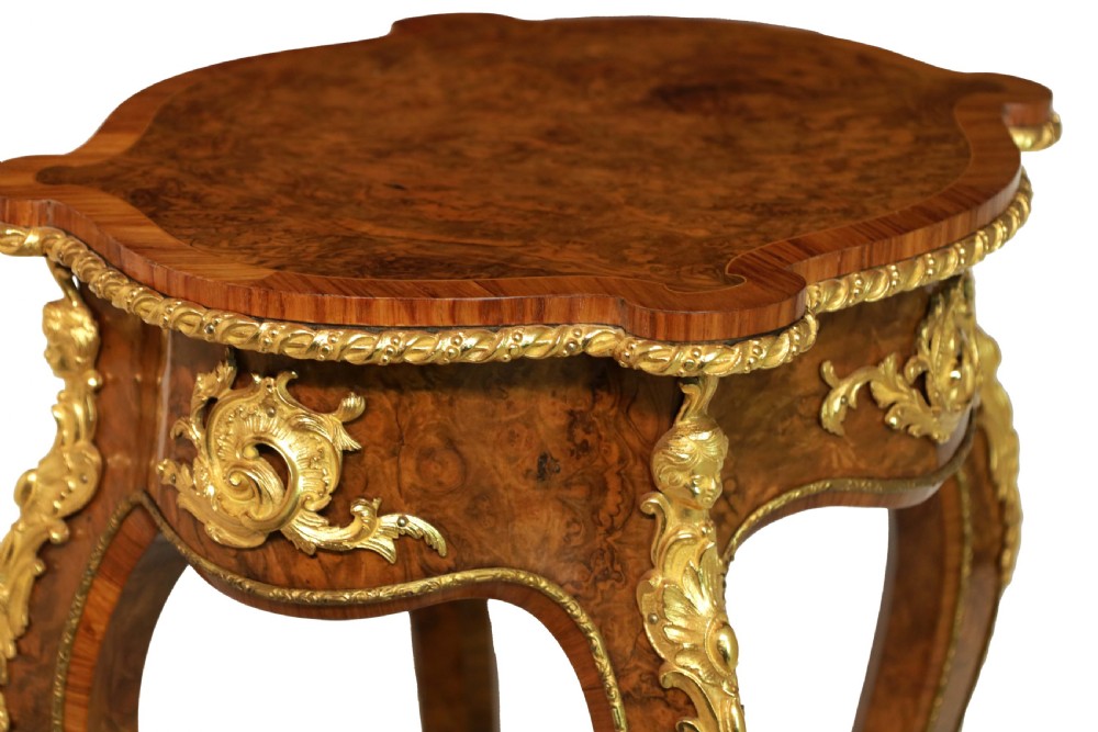 A Victorian burr walnut occasional table featuring a serpentine-edged top, cabriole legs, and ornate gilt bronze mounts along the apron and feet. View V