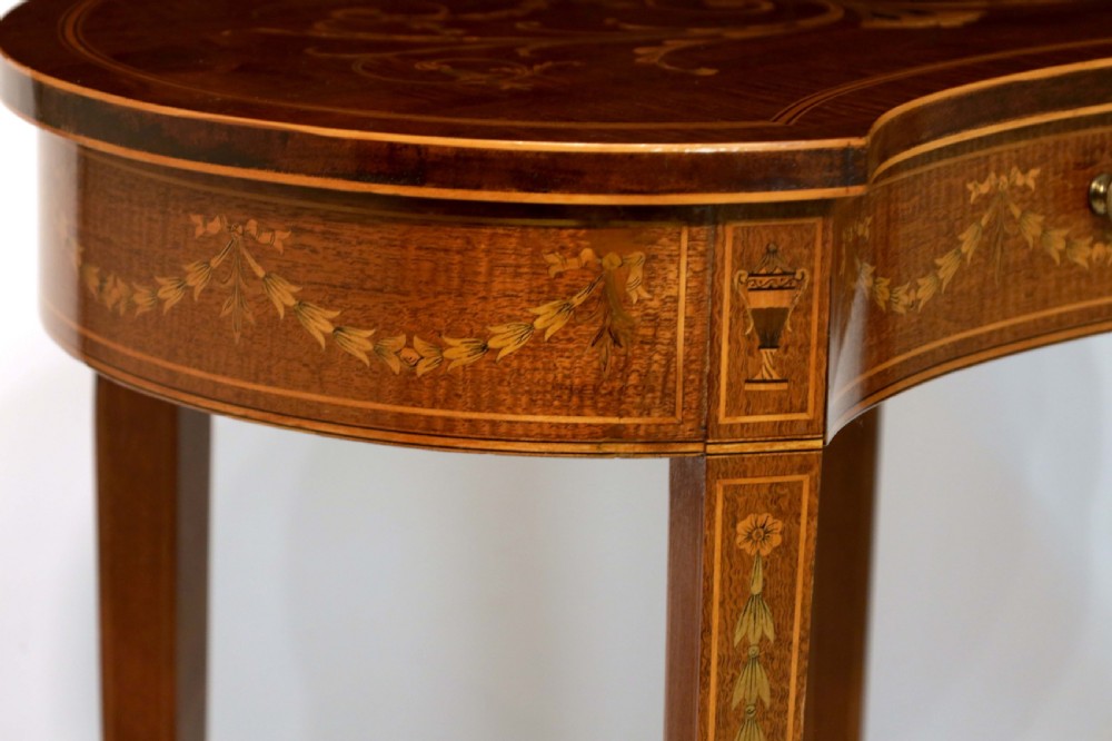 A late Victorian kidney-shaped mahogany side table featuring decorative floral marquetry inlay, slender tapered legs, a small apron drawer, and a lower tier shelf. View III