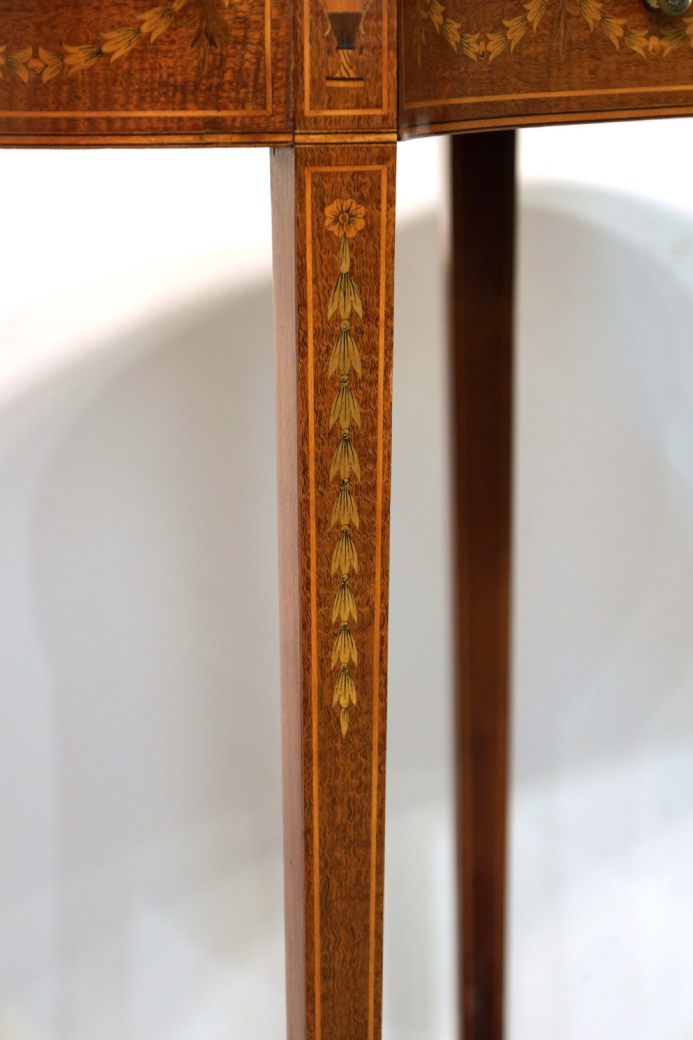 A late Victorian kidney-shaped mahogany side table featuring decorative floral marquetry inlay, slender tapered legs, a small apron drawer, and a lower tier shelf. View V